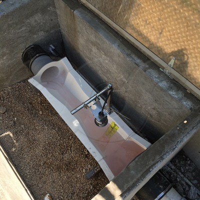a fiberglass trapezoidal flume with end adapters measuring pipe flow in a concrete vault