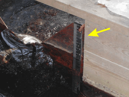 staff gauge mounted on the face of a v-notch weir plate