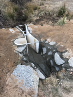a Parshall flume with stilling well and staff gauge measuring irrigation flows